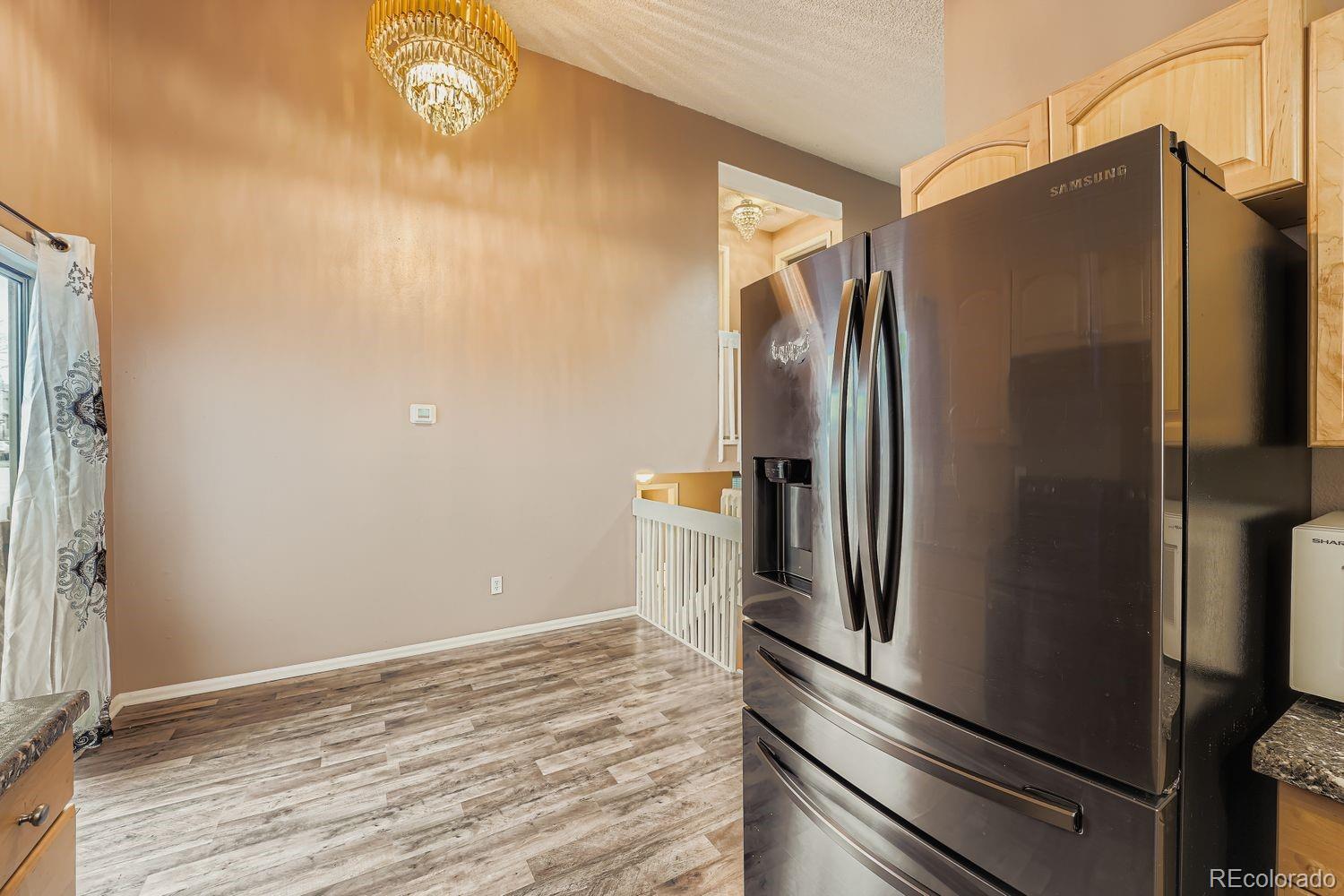17365 East Rice Circle, Unit A Aurora, CO 80015 - Photo 6 of 18 a view of a refrigerator in kitchen and an empty room