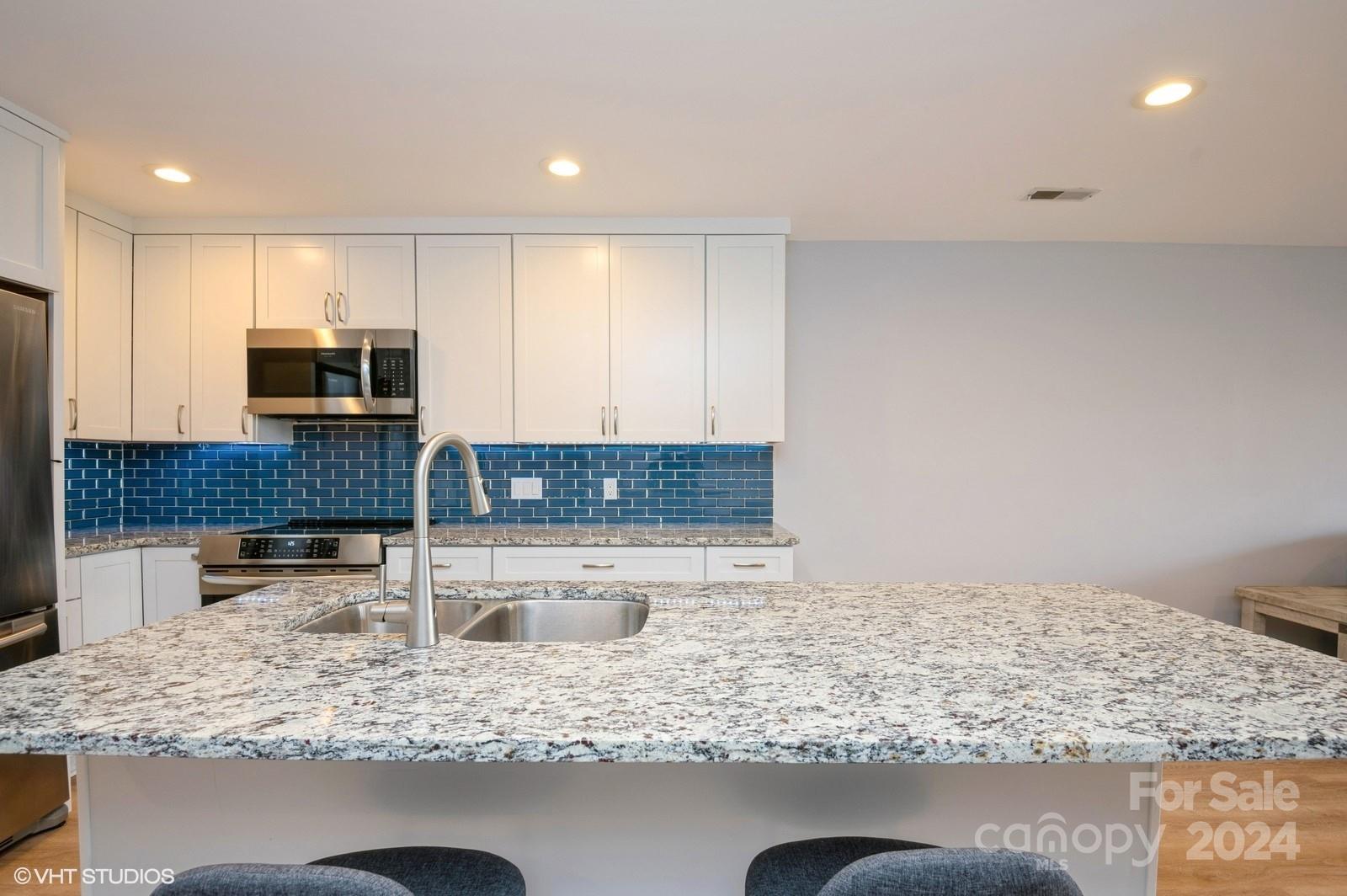 13822 Queens Harbor Road, Unit H Charlotte, NC 28278 - Photo 7 of 37 a kitchen with kitchen island granite countertop a sink and stove