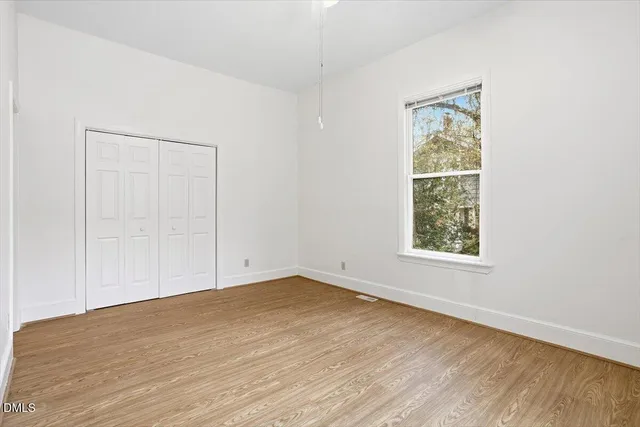 an empty room with wooden floor and windows