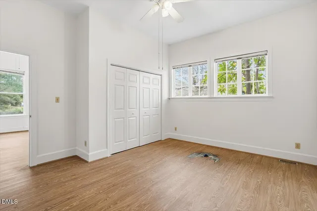 an empty room with wooden floor and windows