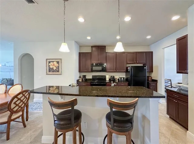 a kitchen with stainless steel appliances granite countertop a stove a sink a microwave a dining table and chairs