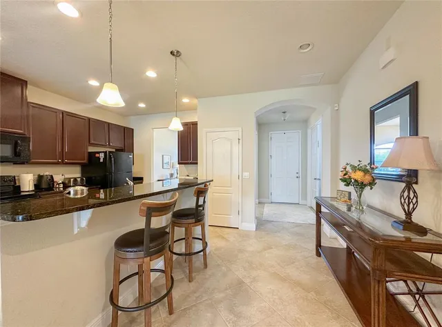 a large kitchen with kitchen island granite countertop lots of white cabinets appliances and furniture