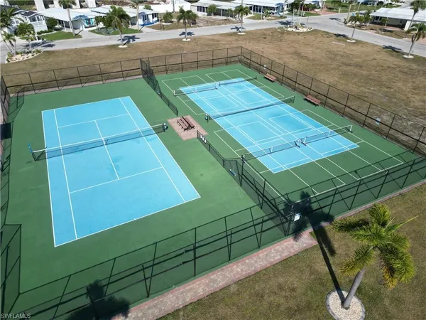 a view of a tennis ground with large trees