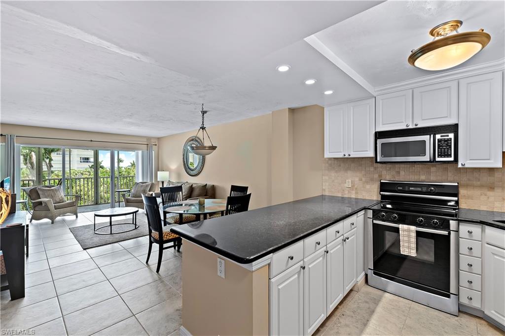 1 Bluebill Avenue, Unit 409 Naples, FL 34108 - Photo 11 of 17 a kitchen with stainless steel appliances granite countertop a stove a sink and a microwave