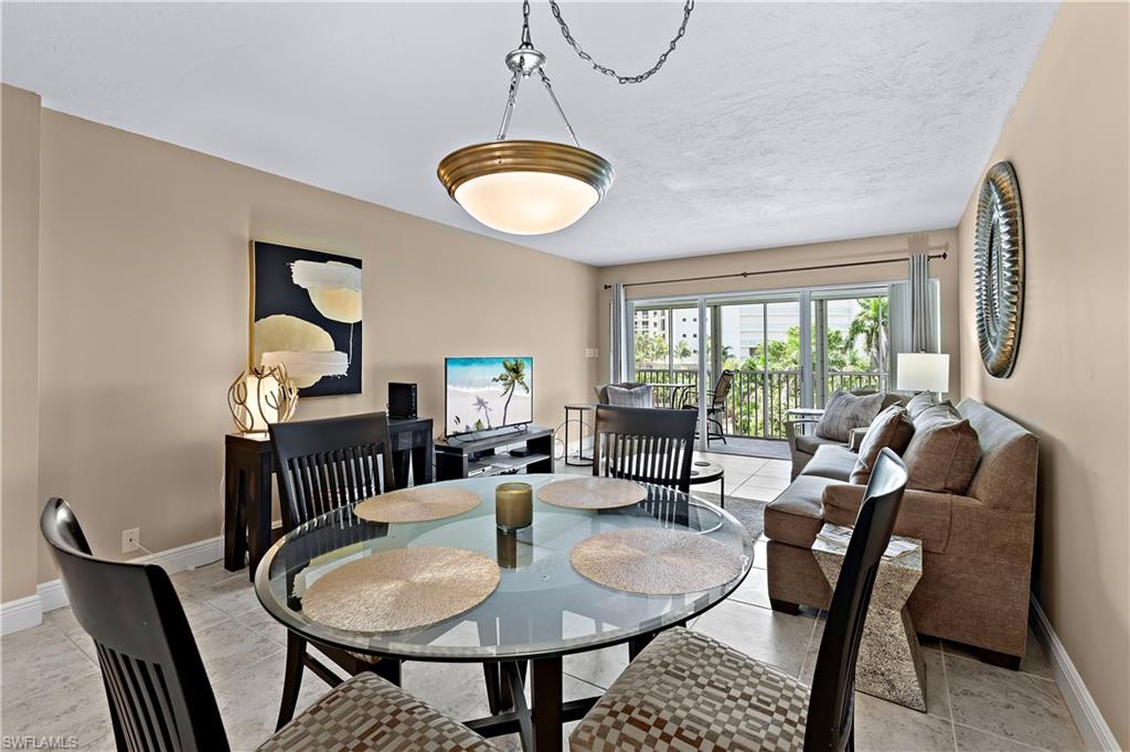 1 Bluebill Avenue, Unit 409 Naples, FL 34108 - Photo 2 of 17 a dining room with furniture a rug and a chandelier