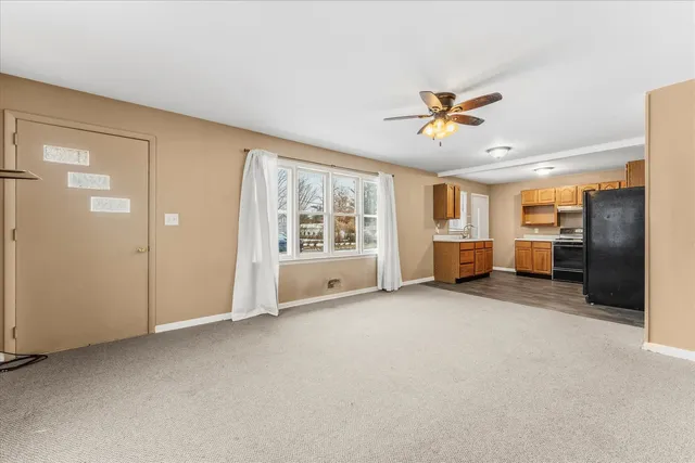an empty room with chandelier fan and windows