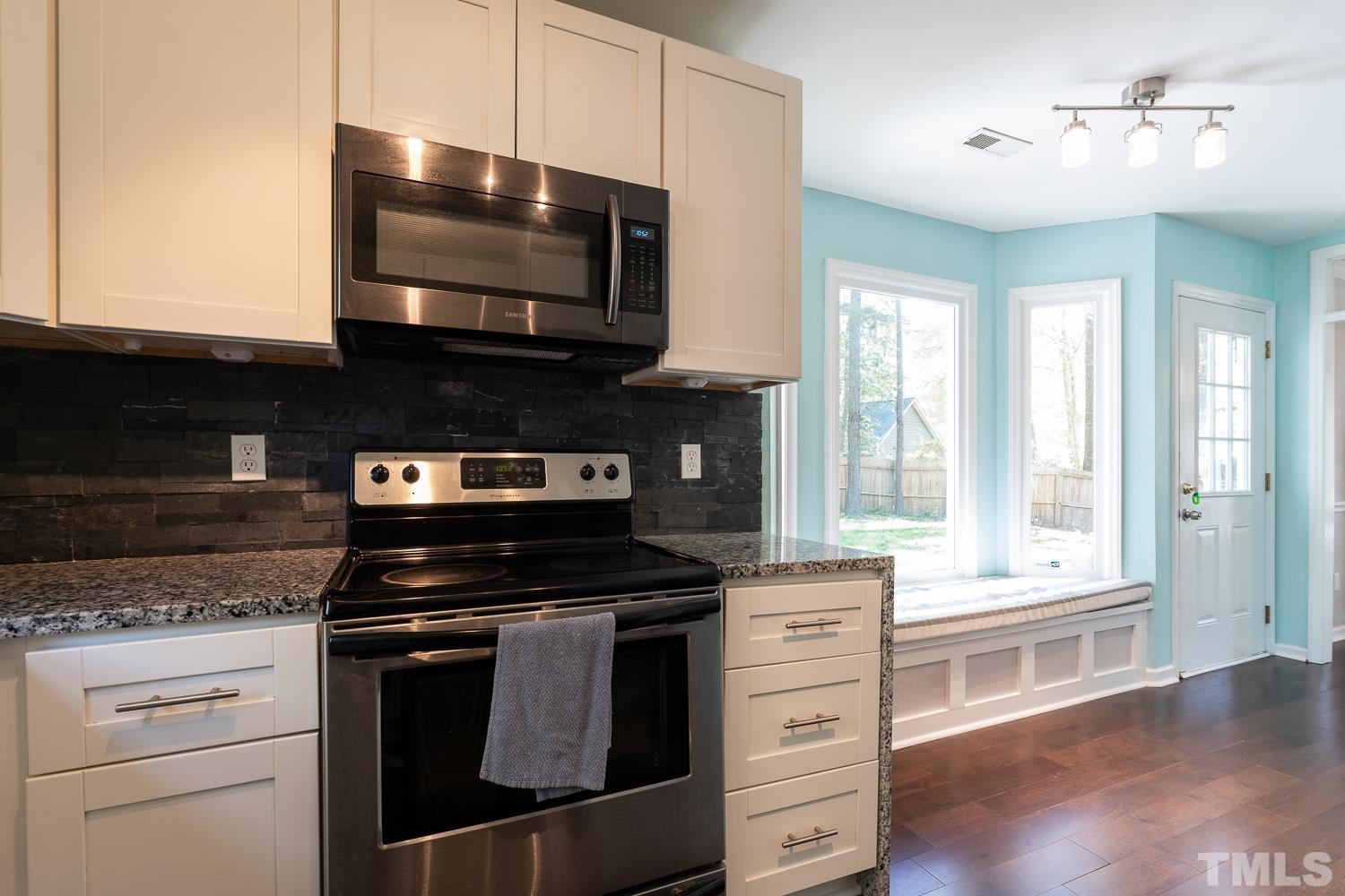 3604 Norway Court Raleigh, NC 27616 - Photo 6 of 26 a kitchen with stainless steel appliances kitchen island granite countertop a stove and a microwave