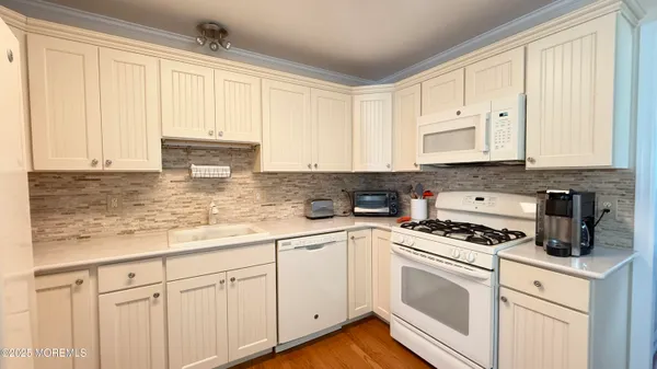 a kitchen with granite countertop white cabinets and white appliances