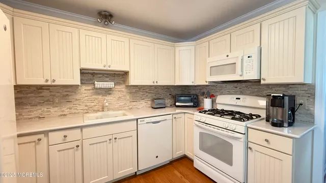 a kitchen with granite countertop white cabinets and white appliances