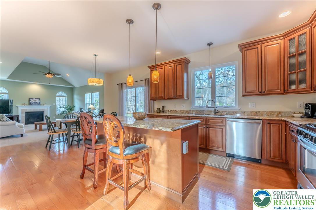 3505 Woodbyne Road Hellertown, PA 18055 - Photo 11 of 66 a open kitchen with stainless steel appliances granite countertop a stove top oven a sink a dining table and chairs with wooden floor