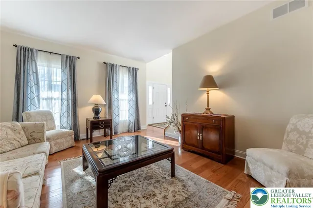 a view of a dining room and livingroom with furniture wooden floor a rug a painting and a chandelier