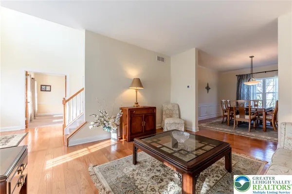 a view of a dining room and livingroom with furniture wooden floor a rug a painting and a chandelier