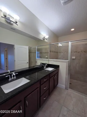 a bathroom with a granite countertop sink a mirror and a shower
