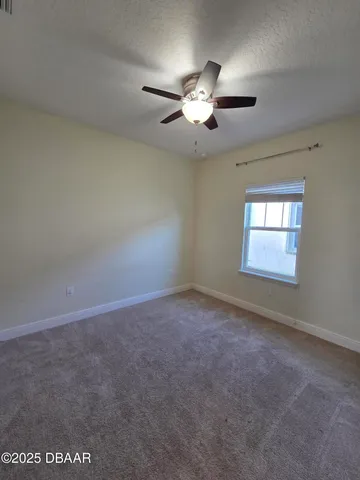 en empty room with windows and chandelier fan
