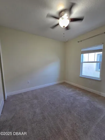 an empty room with a chandelier fan and windows