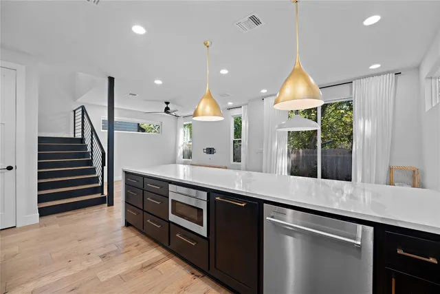 a kitchen with stainless steel appliances granite countertop a sink a stove and a wooden floors