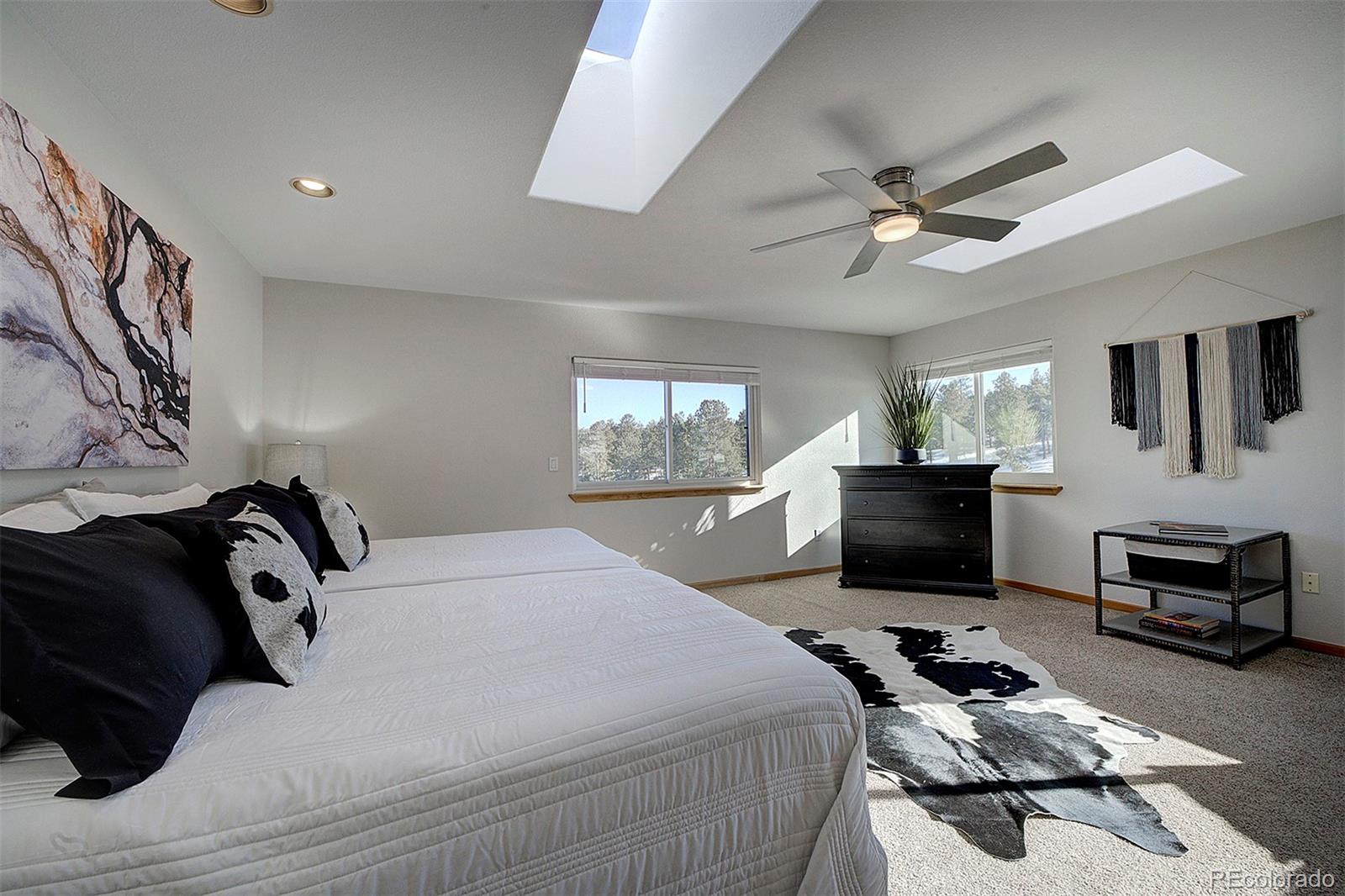 5371 Hazel Road Evergreen, CO 80439 - Photo 30 of 47 a bedroom with a bed a dresser and a chandelier