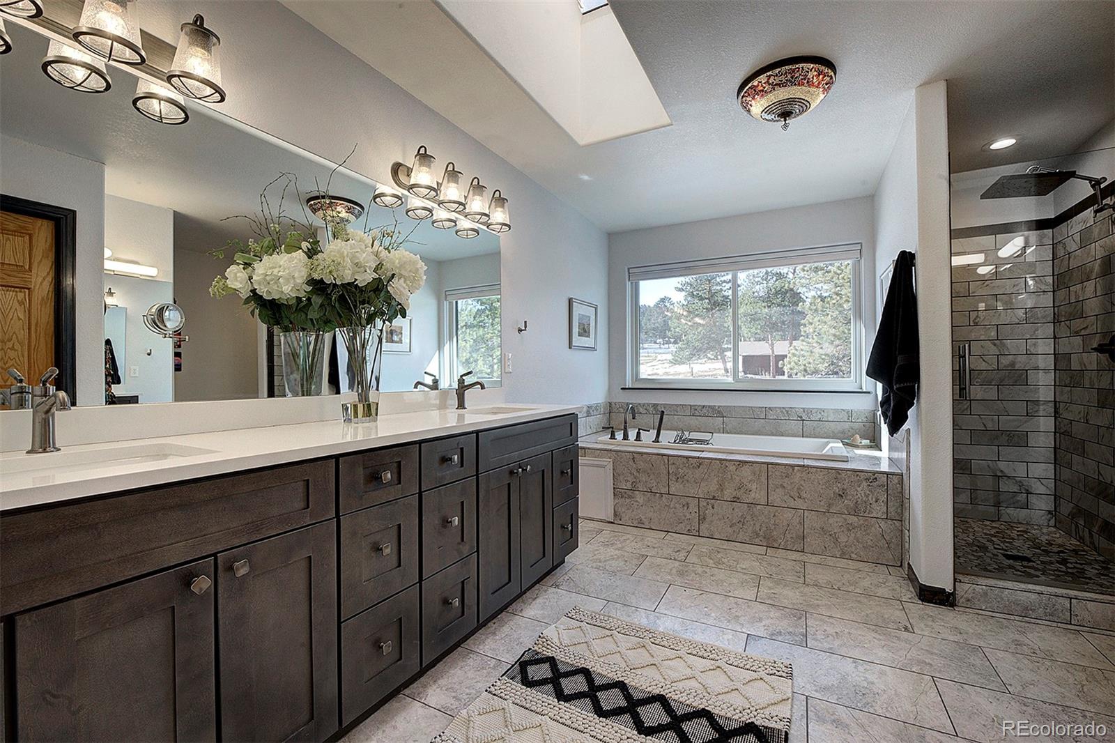 5371 Hazel Road Evergreen, CO 80439 - Photo 31 of 47 a bathroom with a double vanity sink a large mirror and a bathtub