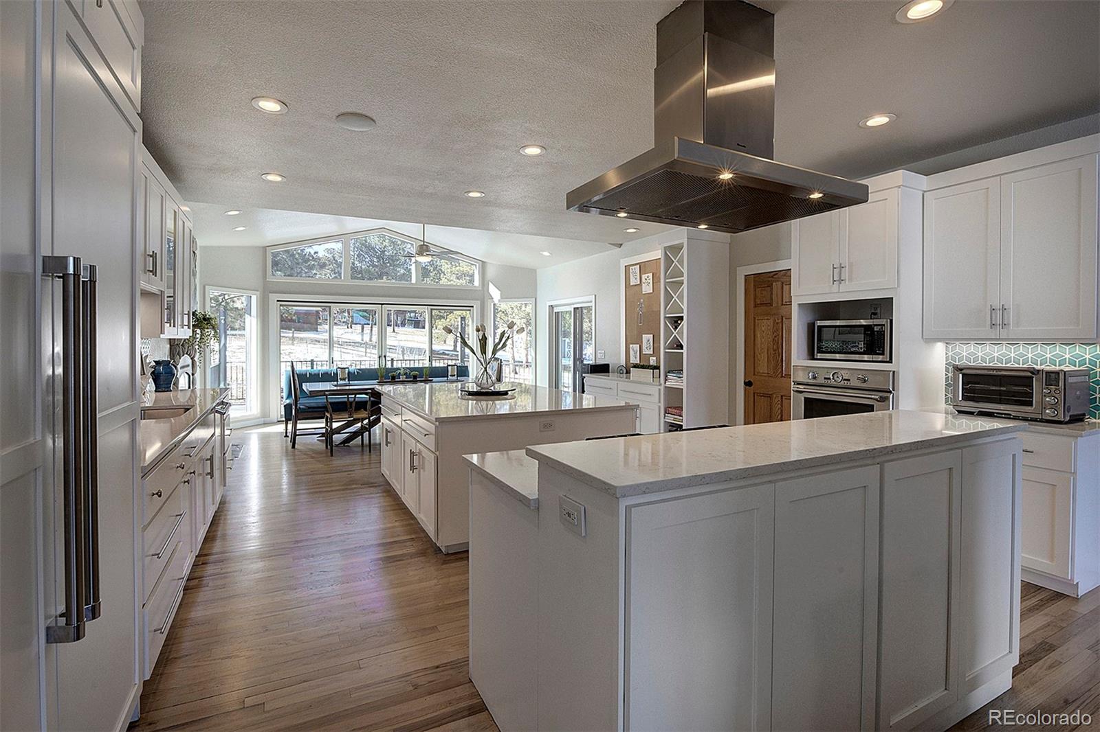 5371 Hazel Road Evergreen, CO 80439 - Photo 9 of 47 a kitchen with stainless steel appliances a refrigerator a stove top oven a sink dishwasher and white cabinets with wooden floor