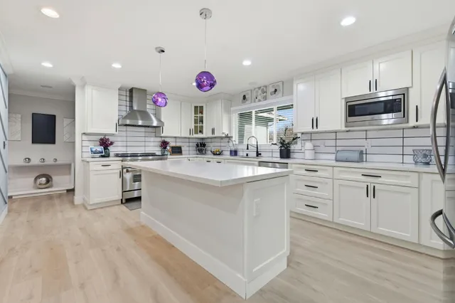 a kitchen with kitchen island granite countertop stainless steel appliances cabinets a sink and a counter top space