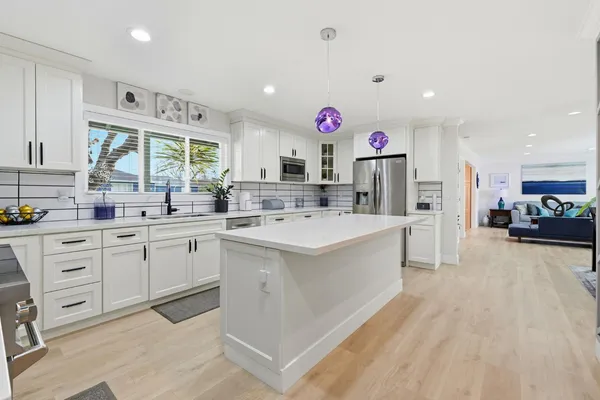 a large white kitchen with a lot of counter space and a sink