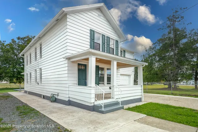 a view of a white house with a yard and plants