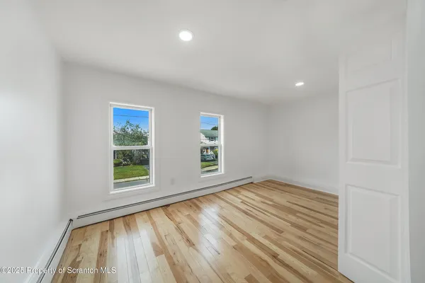 an empty room with wooden floor and windows