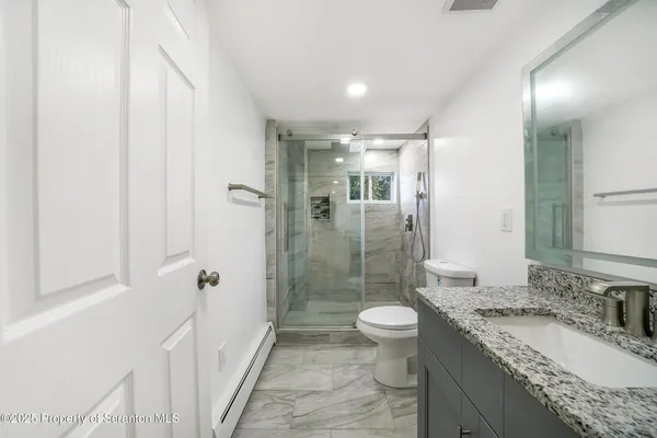 a bathroom with a granite countertop sink a toilet a mirror and shower