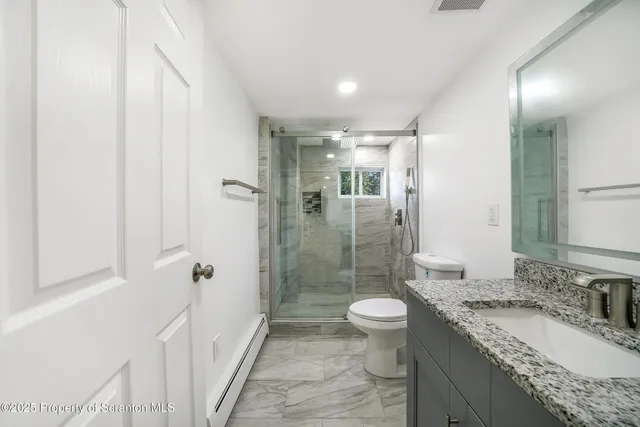 a bathroom with a granite countertop sink a toilet a mirror and shower