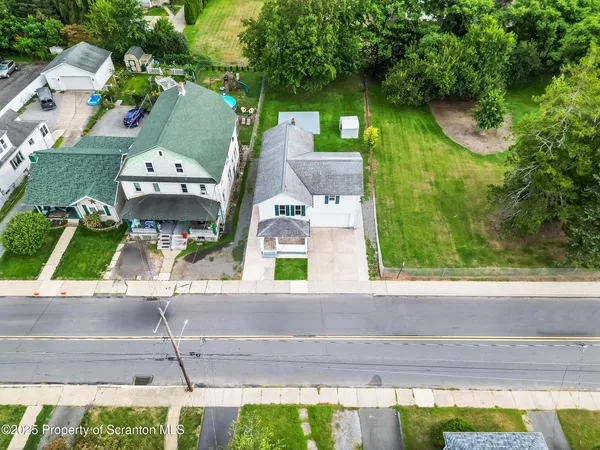 an aerial view of a house with a yard and large trees
