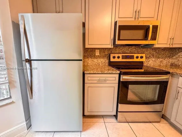 a white refrigerator freezer and a stove sitting inside of a kitchen