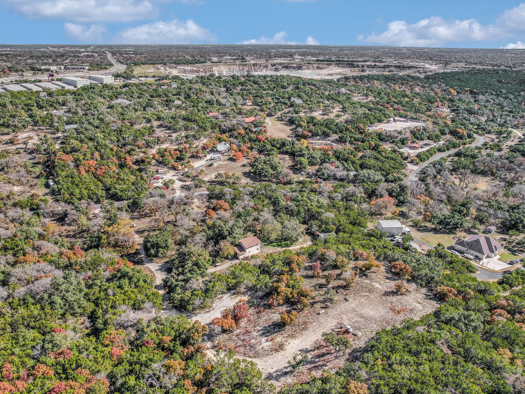 13404 Cedar Lime Road Leander, TX 78641 - Photo 3 of 28 An aerial panorama reveals a vast, tree-filled landscape with scattered residences and distant commercial structures under a broad sky.
