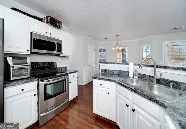 a kitchen with granite countertop a sink stainless steel appliances and white cabinets