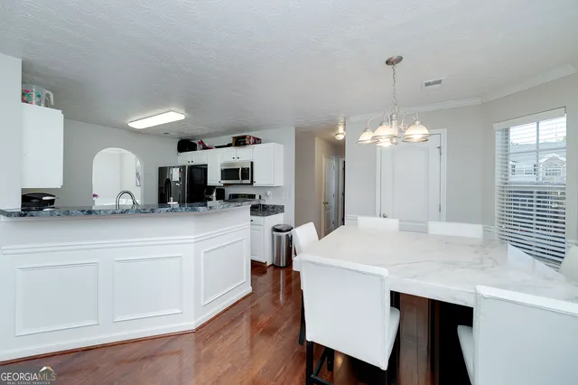 a kitchen with stainless steel appliances a table chairs in it and white cabinets