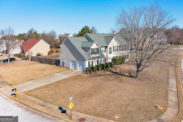 a view of a white house next to a road and yard
