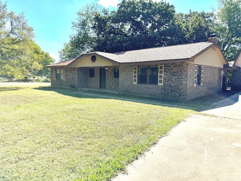 a front view of house with yard and trees in the background