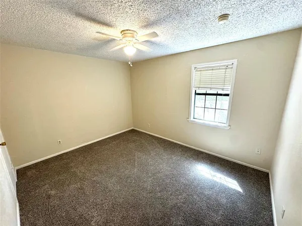 an empty room with a chandelier fan and windows
