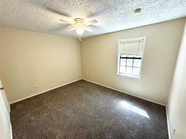 an empty room with a chandelier fan and windows