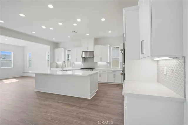 a large white kitchen with kitchen island a sink a stove a refrigerator and white cabinets