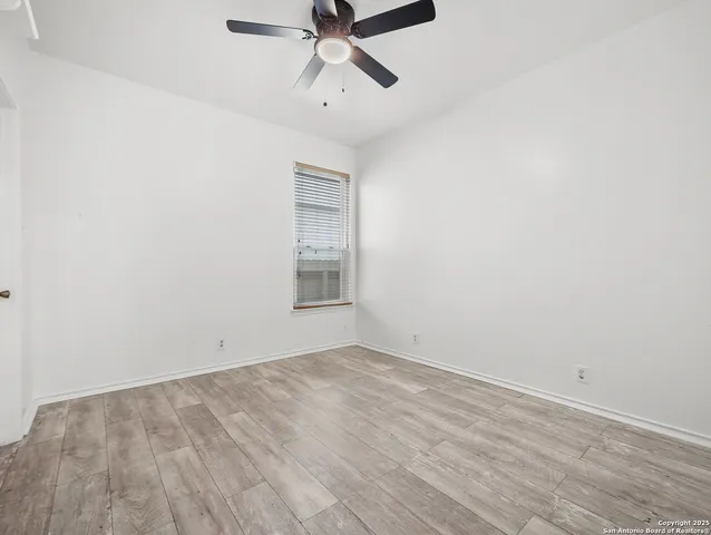 an empty room with a ceiling fan and window