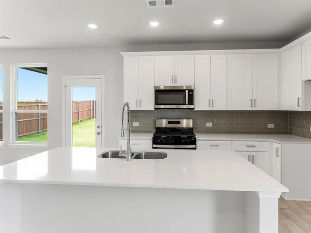 a kitchen with stainless steel appliances a stove a sink a microwave a refrigerator a counter top space and cabinets