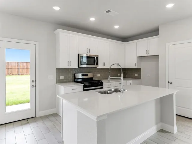 a kitchen with a sink a stove a microwave a center island and cabinets