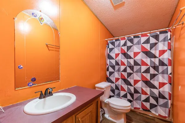 a bathroom with a granite countertop sink toilet a mirror and shower