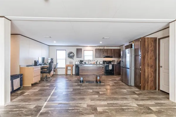 a living room with stainless steel appliances furniture a rug and a kitchen view
