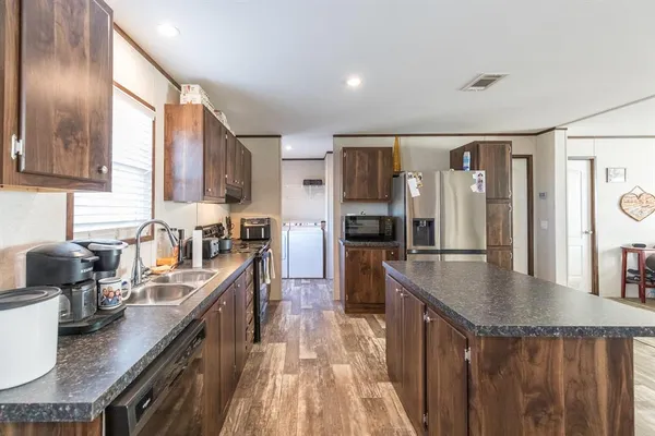 a kitchen with granite countertop a refrigerator a stove a sink dishwasher and cabinets with wooden floor