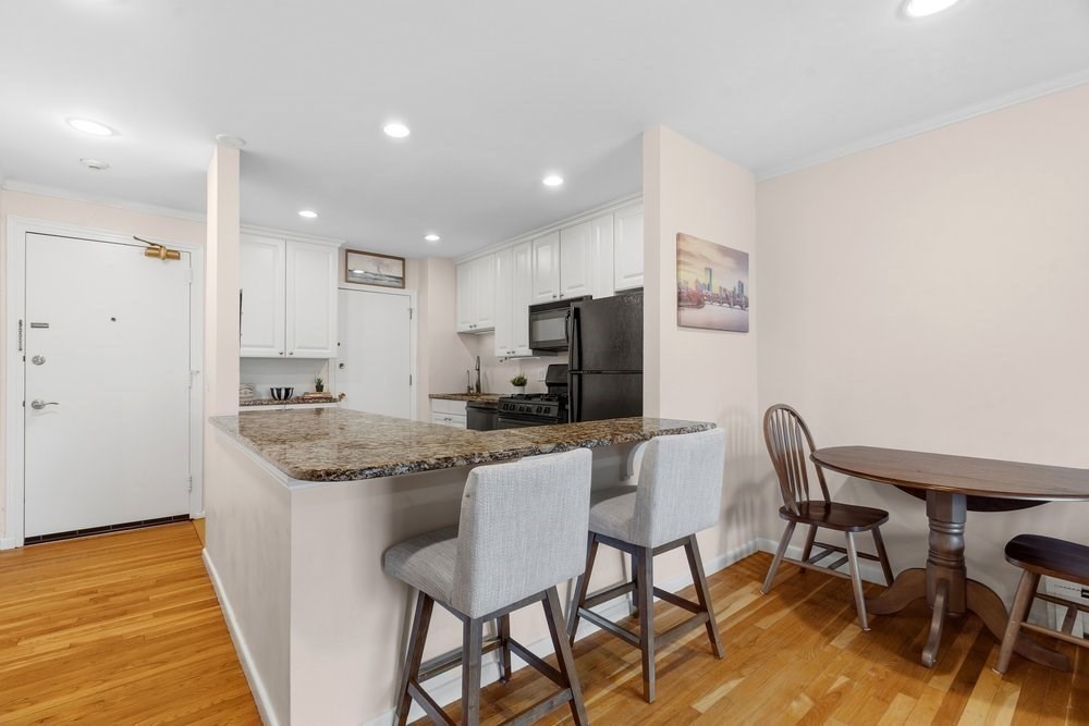 135 Granite Avenue, Unit 49 Boston, MA 02124 - Photo 3 of 14 a kitchen with stainless steel appliances granite countertop a table chairs sink and cabinets