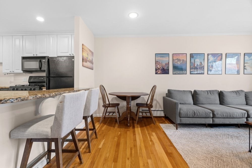 135 Granite Avenue, Unit 49 Boston, MA 02124 - Photo 4 of 14 a living room with furniture a wooden floor and a kitchen view
