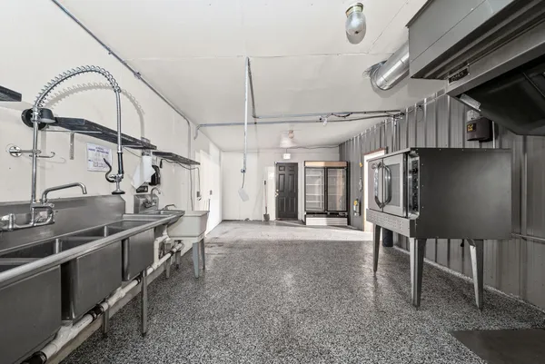 a kitchen with stainless steel appliances kitchen island a table chairs in it and wooden floors