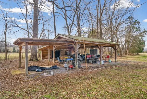 a view of a blue house with large trees and playing area