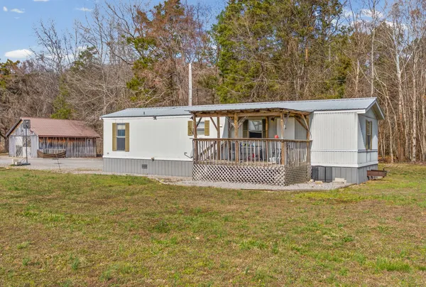 a view of a house with a big yard and large tree
